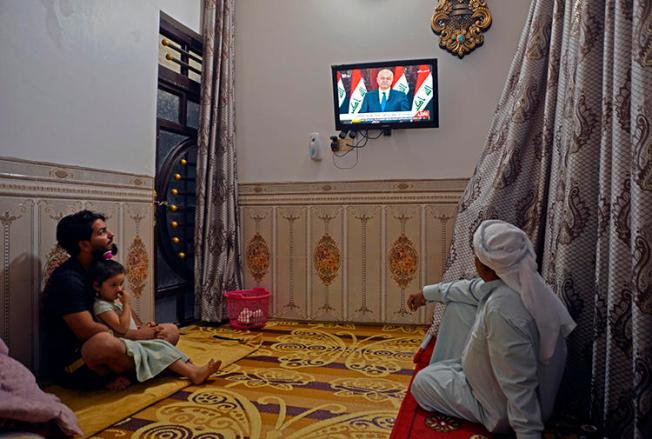 People watch television in Najaf, Iraq, on October 31, 2019. Iraq's media regulator recently ordered the closure of 12 broadcast outlets throughout the country. (AFP/Haidar Hamdani)