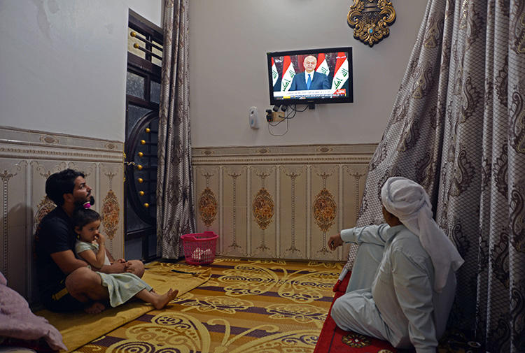 People watch television in Najaf, Iraq, on October 31, 2019. Iraq's media regulator recently ordered the closure of 12 broadcast outlets throughout the country. (AFP/Haidar Hamdani)