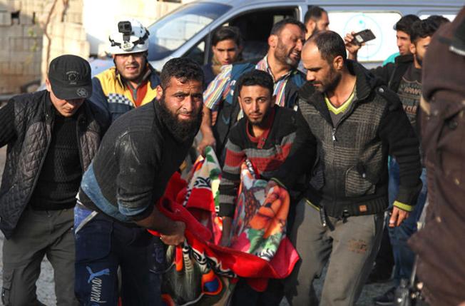 Residents and a rescue worker carry the body of a man killed in an airstrike in Kfar Rumah, in Syria's Idlib province, on November 10, 2019. A journalist for the Kafr Rumah Media Office was killed during shelling in the town. (AFP/Abdulaziz Ketaz)