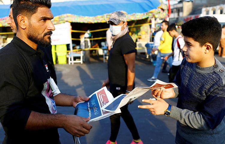 A demonstrator distributes a newspaper in Baghdad, Iraq, on November 17, 2019. A journalist was recently abducted and a broadcaster's office attacked amid the demonstrations. (Reuters/Thaier al-Sudani)