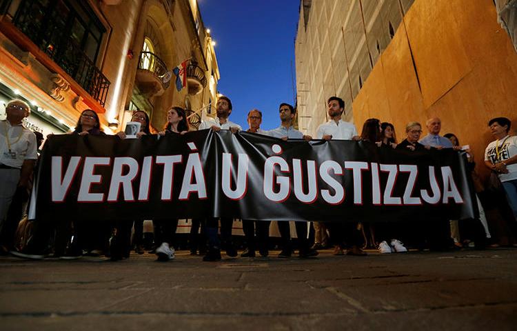 Friends and family members of journalist Daphne Caruana Galizia carry a banner calling for "Truth and Justice" in the investigation into her murder, in Valletta, Malta, on October 16, 2019. Her family and the Maltese government recently reached an agreement on the nature of the investigation. (Reuters/Darrin Zammit Lupi)