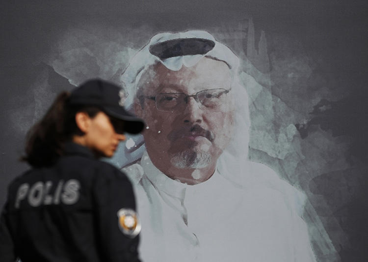 A police officer walks past a picture of Saudi journalist Jamal Khashoggi on October 2, 2019, prior to a ceremony near the Saudi consulate in Istanbul to mark the one-year anniversary of his murder. His killing and the Maguindanao massacre are emblematic of the impunity that characterizes nearly all journalist killings. (AP/Lefteris Pitarakis)
