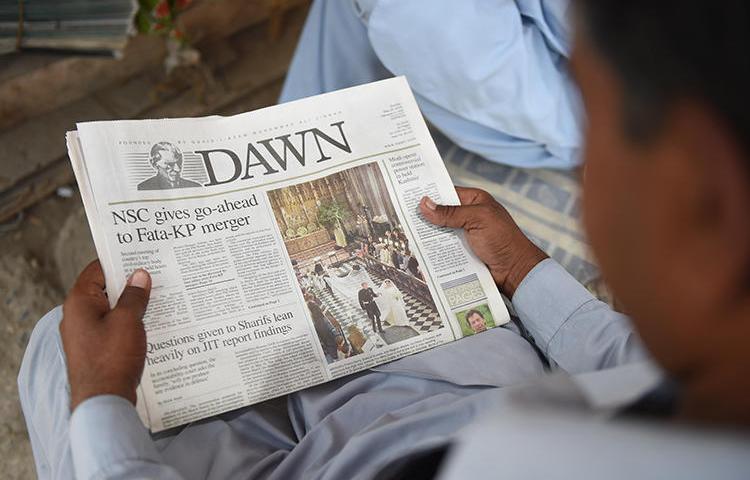 A man reads a copy of the Dawn English-language newspaper in Karachi, Pakistan, on May 20, 2018. Demonstrators recently besieged Dawn's Islamabad offices and threatened its staffers. (AFP/Rizwan Tabassum)