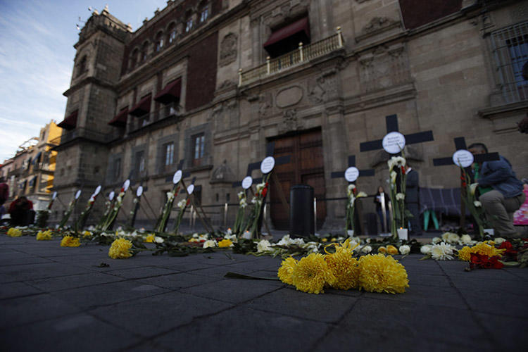 Flores y cruces llevan el nombre de periodistas y personas defensoras de los derechos humanos asesinados en los primeros tres meses de la gestión del presidente Andrés Manuel López Obrador, en febrero de 2019 en Ciudad de México. Como mínimo, dos de los periodistas que fueron asesinados por su labor en 2019, se habían incorporado a un mecanismo de protección. (AP/Rebecca Blackwell)