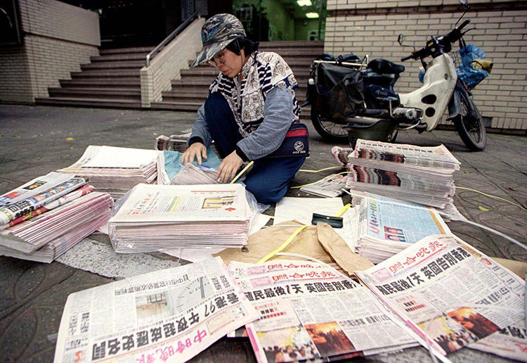A Taipei newspaper delivery woman counts piles of evening newspapers bearing headlines of Hong Kong's midnight handover to Chinese rule on June 30, 1997. (Reuters)