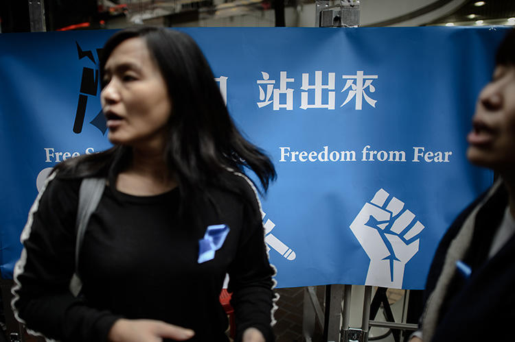 2014年2月28日，幾名香港女士站在桌邊的一條橫幅旁，為聲援自由派《明報》前總編劉進圖收集簽名。襲擊劉進圖的幕後元兇至今未知。（法新社/ Philippe Lopez）