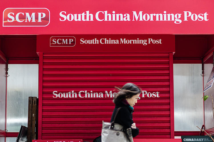 2015年12月12日，在中國電商巨頭阿里巴巴收購英文報紙《南華早報》後，一位行人路過一家關門的報攤，門上印有《南華早報》的商標。（法新社/ Anthony Wallace）