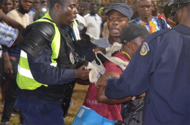 Christopher Walker (center, in red) is seen being removed from the press area in Samuel Kanyon Doe Sport Stadium in Monrovia, Liberia, on January 23, 2020. (FrontPage Africa)