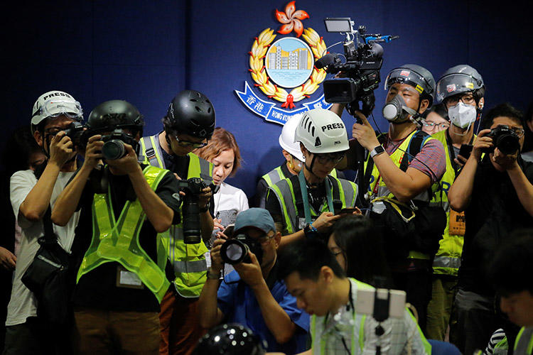 2019年6月13日，香港的新聞攝影記者戴上頭盔和防毒面具參加一次警方新聞發佈會，以抗議警方在前一天的反引渡法案抗議活動中對新聞工作者施暴。（路透社/ Thomas Peter）