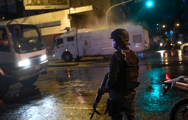 La Guardia Nacional Bolivariana usa un cañón de agua para rociar desinfectante como una medida preventiva contra el contagio del nuevo coronavirus, en Caracas, Venezuela, el 21 de marzo de 2020 (AP/Matias Delacroix)