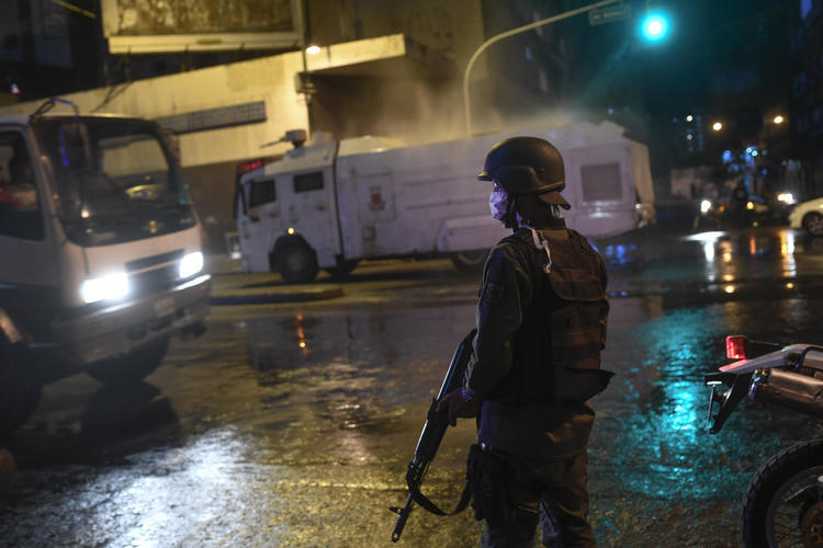 La Guardia Nacional Bolivariana usa un cañón de agua para rociar desinfectante como una medida preventiva contra el contagio del nuevo coronavirus, en Caracas, Venezuela, el 21 de marzo de 2020 (AP/Matias Delacroix)