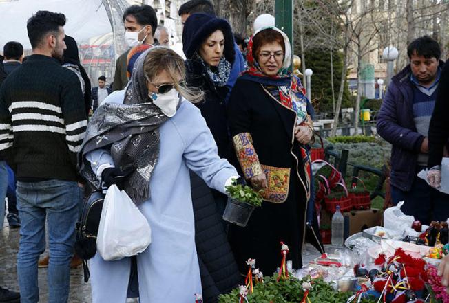 An Iranian woman wearing a protective face mask chooses traditional items ahead of Nowruz, the national New Year celebration, at the Tajrish Bazaar in the capital Tehran on March 19, 2020, despite the heavy death toll due the novel coronavirus in the country. Amid the coronavirus pandemic, the government has covered up crucial information and threatened journalists. (AFP/Stringer)