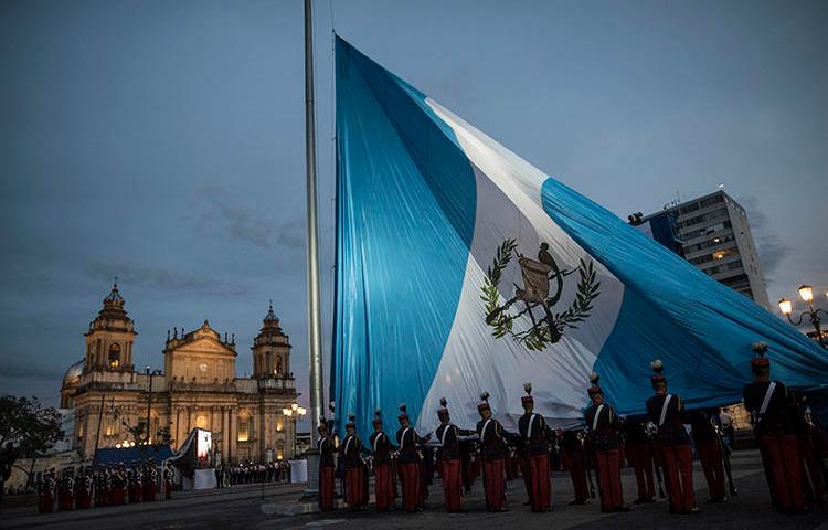 Soldados guatemaltecos izan la bandera nacional en la Plaza de la Constitución, Ciudad de Guatemala, en septiembre de 2019. Con la toma de posesión de un nuevo mandatario, el país tiene la oportunidad de mejorar las condiciones para el ejercicio del periodismo. (AP/Oliver de Ros)