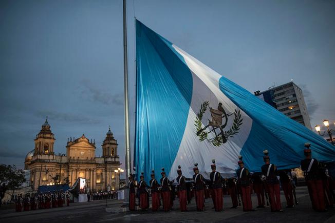 Soldados guatemaltecos izan la bandera nacional en la Plaza de la Constitución, Ciudad de Guatemala, en septiembre de 2019. Con la toma de posesión de un nuevo mandatario, el país tiene la oportunidad de mejorar las condiciones para el ejercicio del periodismo. (AP/Oliver de Ros)