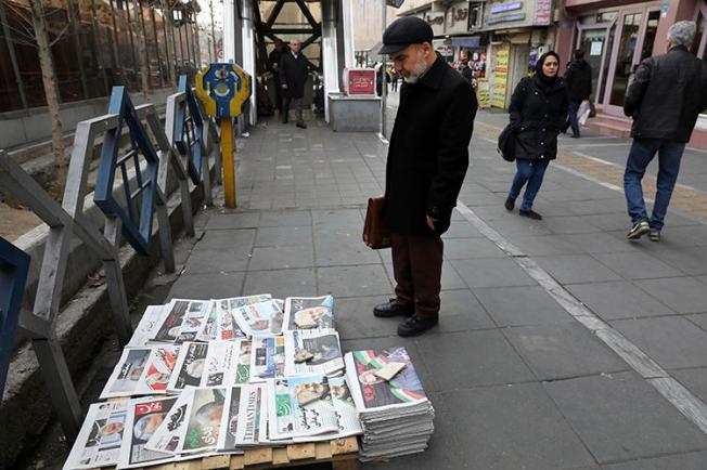 A man reads newspapers in Tehran, Iran, on January 4, 2020. The country recently banned all newspaper printing and distribution, citing fears of spreading COVID-19. (AP/Vahid Salemi)