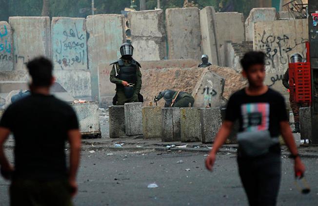 Security forces and protesters are seen in Baghdad, Iraq, on February 22, 2020. Iraqi riot police recently shot AFP photographer Ahmad al-Rubaye with rubber pellets. (AP/Hadi Mizban)