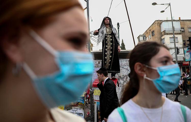 Ultra-Orthodox Jewish girls wear face masks during celebrations of the Purim festival in Bnei Brak, Israel, on March 10, 2020. CPJ recently spoke with Laura Adkins, an Orthodox Jewish editor at the Jewish Telegraph Agency. (AP/Oded Balilty)