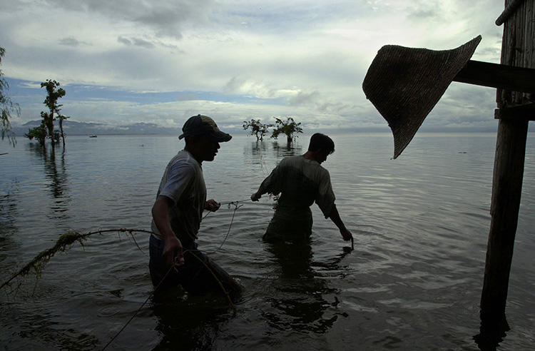 Pescadores en medio de sus labores en el lago Izabal, Guatemala, en 2002. Los periodistas que cubren distintas problemáticas de la región, como el impacto de la contaminación industrial, son objeto de amenazas y demandas judiciales. (AP/Jaime Puebla)