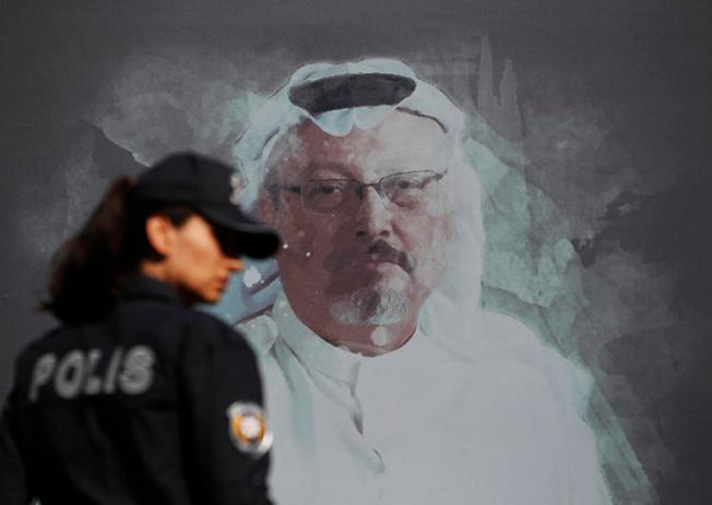 A police officer is seen near a picture of slain Saudi journalist Jamal Khashoggi in Istanbul, Turkey, on October 2, 2019. Today, Turkey indicted 20 Saudi nationals in Khashoggi's killing. (AP/Lefteris Pitarakis)