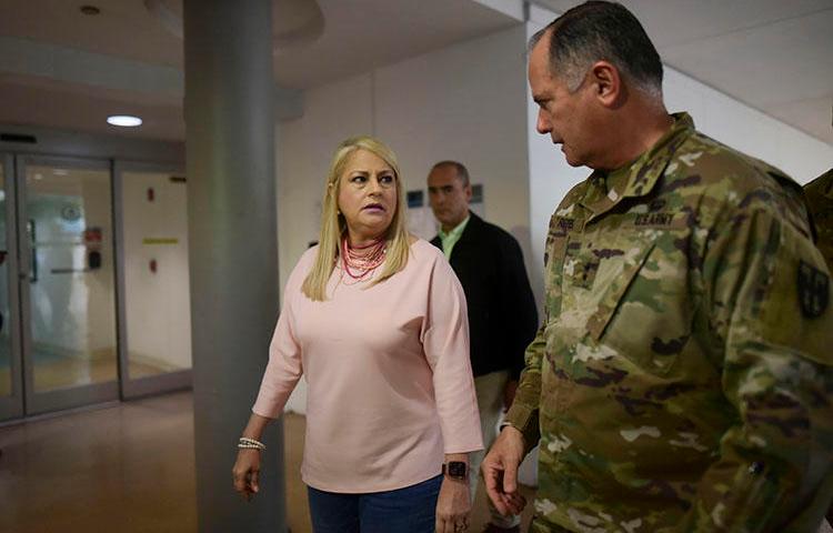 La gobernadora Wanda Vázquez y el general de la Guardia Nacional José Reyes recorrieron las estaciones de detección establecidas para detectar síntomas del nuevo coronavirus en los pasajeros que llegan al Aeropuerto Luis Muñoz Marín en Carolina, Puerto Rico, el 16 de marzo de 2020. La reportera Bárbara Figueroa Rosa describió los desafíos de cubrir Brote de coronavirus de Puerto Rico. (Foto AP/Carlos Giusti)