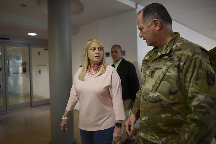 La gobernadora Wanda Vázquez y el general de la Guardia Nacional José Reyes recorrieron las estaciones de detección establecidas para detectar síntomas del nuevo coronavirus en los pasajeros que llegan al Aeropuerto Luis Muñoz Marín en Carolina, Puerto Rico, el 16 de marzo de 2020. La reportera Bárbara Figueroa Rosa describió los desafíos de cubrir Brote de coronavirus de Puerto Rico. (Foto AP/Carlos Giusti)