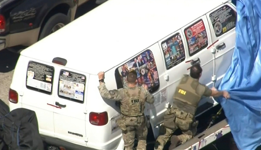 A video frame shows FBI agents on October 26, 2018, pulling a tarp over a van from Plantation, Florida, covered in pro-Trump stickers. The van was investigated in connection with package bombs sent to the CNN newsroom in New York and to other perceived critics of President Trump. (WPLG-TV via AP)