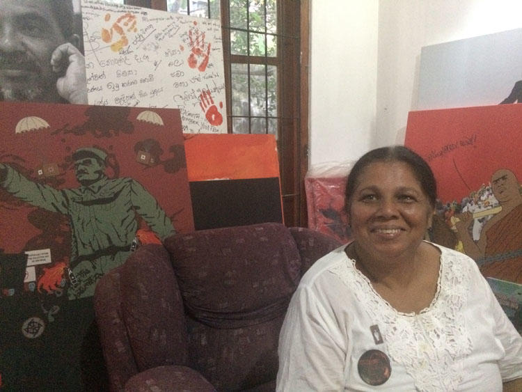 Sandya Eknelygoda sits in her living room surrounded by graphic artwork created by her sons. (CPJ/Aliya Iftikhar)