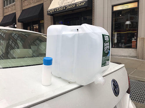 A makeshift sink made by resting a 2.5 gallon water jug with push tap over the edge of photojournalist Angus Mordant's trunk allowing for easy access to hand washing on the job. (Angus Mordant)