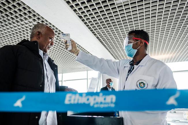 A worker of the Ethiopian Public Health Institute measures a man's temperature in Addis Ababa, on March 17, 2020. Ethiopian police are holding journalist Yayesew Shimelis pending a terrorism investigation. (AFP/Eduardo Soteras)