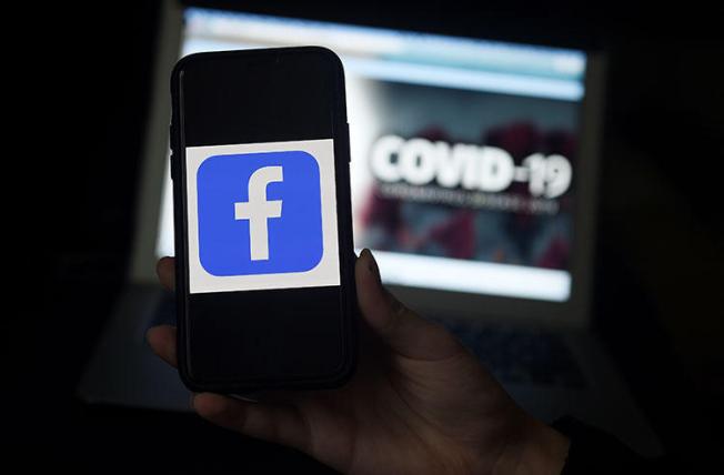 The Facebook logo is displayed on a mobile phone screen photographed on a COVID-19 illustration graphic background on March 25, 2020 in Arlington, Virginia. CPJ and partners called on social media and content sharing platforms to preserve data amid the pandemic. (AFP/Olivier Douliery)