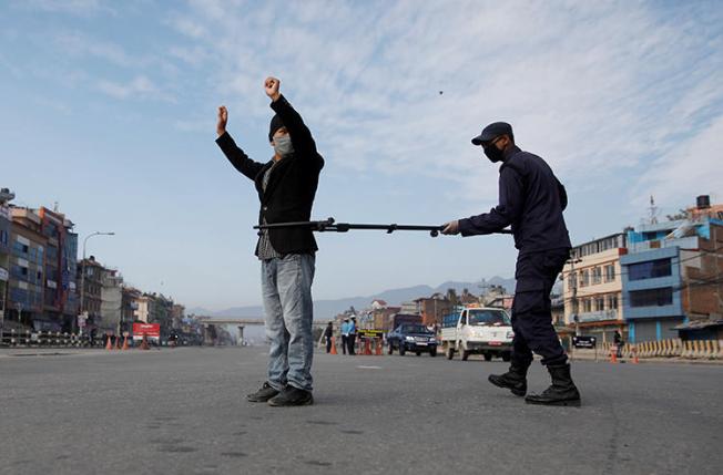 A Nepalese police officer maintains distance as he detains a man defying the lockdown imposed by the government amid concerns about the spread of coronavirus disease (COVID-19), in Kathmandu on March 29, 2020. Several journalists have been detained or obstructed while reporting since the lockdown was imposed. (Reuters/Navesh Chitrakar)