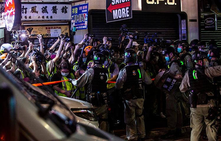 Riot police hold back members of the press in the Mong Kok district of Hong Kong on May 10, 2020. Police attacked and arrested journalists covering that protest. (AFP/Isaac Lawrence)