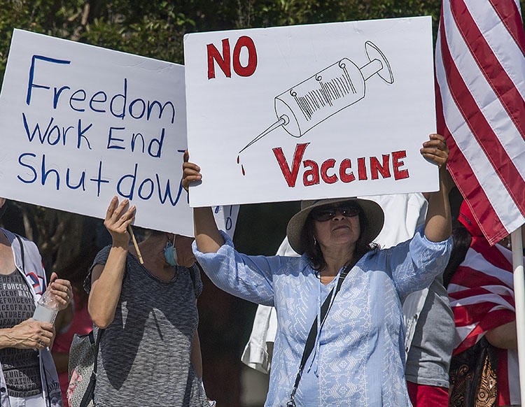 Supporters of U.S. President Donald Trump hold signs during a rally to call for the reopening of California's economy after the lockdown closure, implemented to prevent the spread of the novel coronavirus, in Woodland Hills, California, on May 16, 2020. NY Times reporter Davey Alba recently told CPJ about her experiences covering coronavirus conspiracy theories and facing online harassment. (AFP/Mark Ralston)