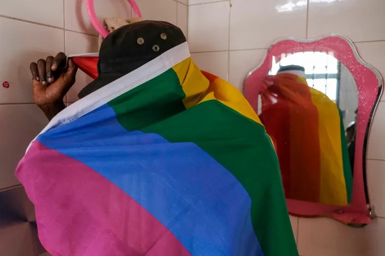 A gay Ugandan man covers himself with a pride flag as he poses for a photograph in Uganda in March 2023. (AP Photo)