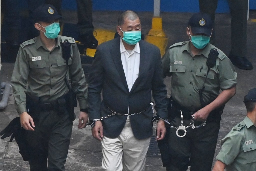 Hong Kong pro-democracy media tycoon Jimmy Lai, handcuffed and chained between two officers, is led into a police van as he heads to court to be charged under the territory's national security law on December 12, 2020 as he is accused of conspiring with foreign forces to endanger national security.