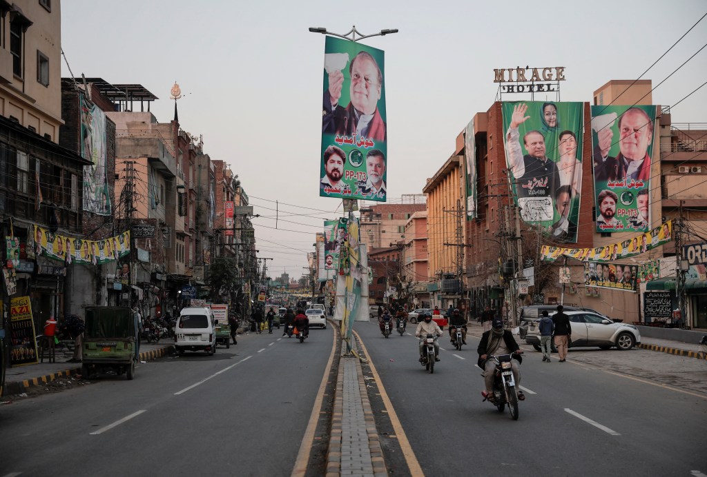 People commute on a street filled with election campaign banners and posters in Lahore, Pakistan, on February 5, 2024.