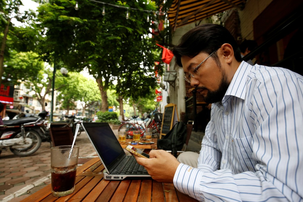 Vietnamese blogger and activist Nguyen Chi Tuyen, also known as Anh Chi, searches the internet on his phone in a cafe in Hanoi, Vietnam, on August 25, 2017.