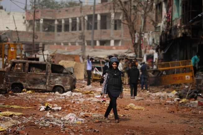 A reporter holds a microphone as she walks through a street vandalized in deadly communal riots in New Delhi, India, on February 27, 2020.