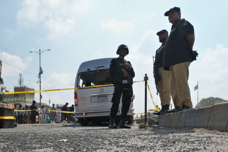 Police officers stand guard at the site of a suicide attack in Karachi, Pakistan, in April 2024.