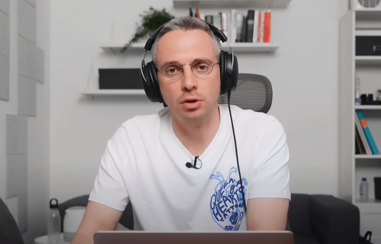 A man wearing headphones talks in front of a laptop.