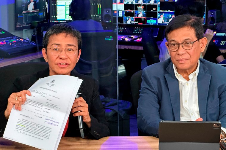 Maria Ressa, Nobel laureate and co-founder of Rappler, displays documents showing the court's decision to allow the news site to keep operating, seated by her lawyer Francis Lim, at a news conference in Rappler's office in the Philippine capital Manila on August 9.