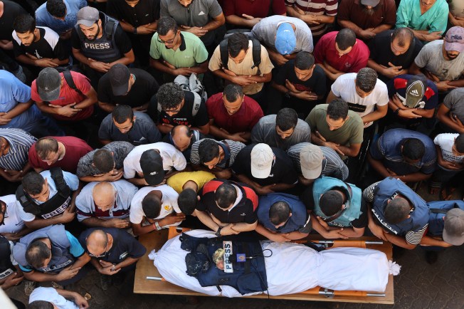 Mourners and colleagues pray over the body of Al Jazeera Arabic journalist Ismail Al Ghoul, killed along with his camera operator Rami Al Refee, in an Israeli strike on July 31, 2024. (Photo: AFP/Omar Al-Qattaa)