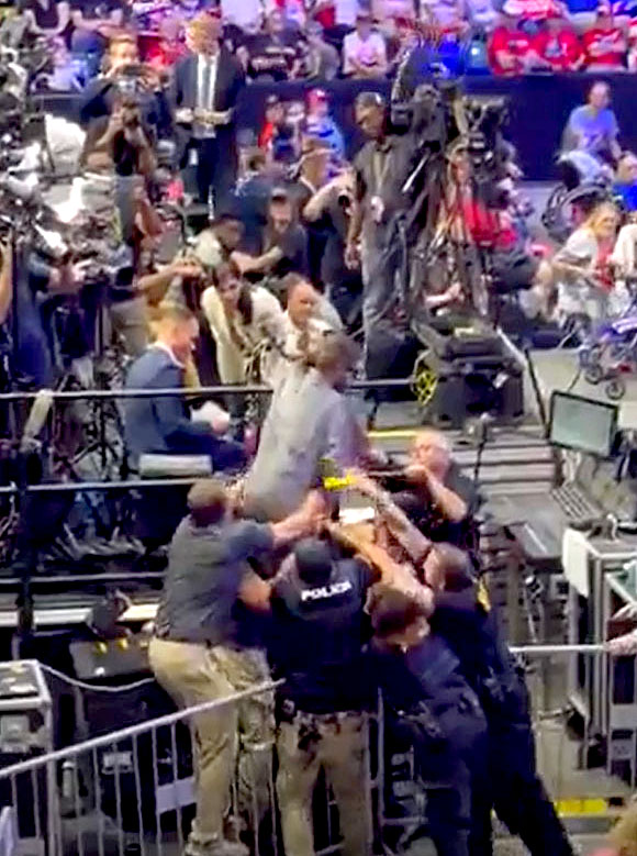 Security and police officers restrain a man who jumped onto the media area at a Pennsylvania rally for Donald Trump on August 30, 2024,, after Trump referred to the press as "the enemy of the people." (Screenshot: CPJ/WJAC-NBC-TV)