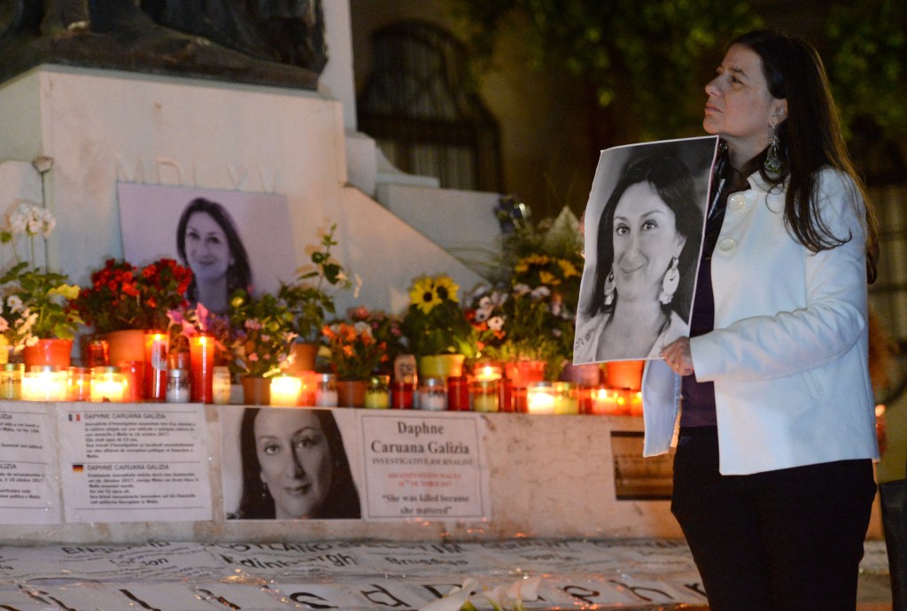 A woman stands beside candles placed in memory of murdered anti-corruption journalist Daphne Caruana Galizia in Valletta, Malta on April 16, 2018.