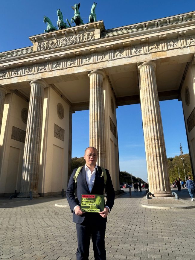 Sebastien Lai, son of imprisoned Hong Kong media publisher Jimmy Lai, holds up a placard calling for his father's release in front of the Branderburg gate during a campaign in Berlin, Germany, October 2024.