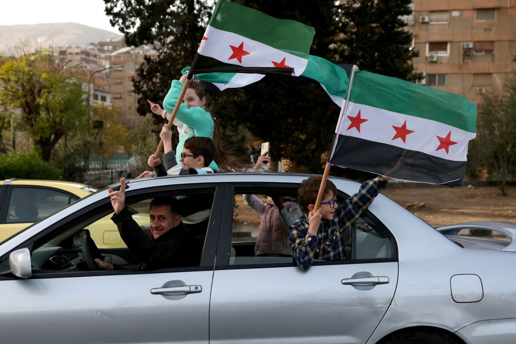 People celebrate with the Syrian opposition flag in Damascus on December 10, 2024, after Bashar al-Assad's oppressive regime was toppled and the former president fled to Russia. (Photo: AFP/Omar Haj Kadour)