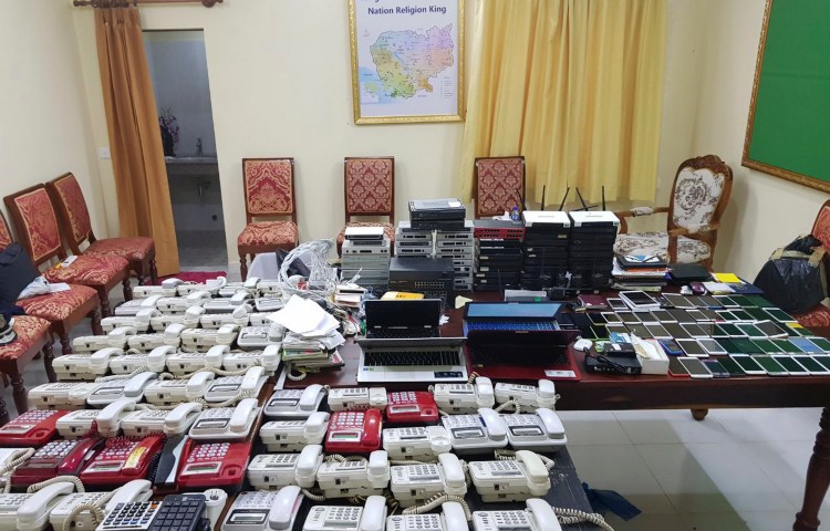 This 2017 photo released by the Cambodian authorities shows numerous telephones, cell phones, and computer networking equipment confiscated from suspected internet phone scammers.