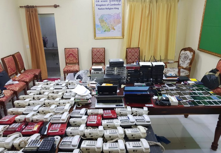 This 2017 photo released by the Cambodian authorities shows numerous telephones, cell phones, and computer networking equipment confiscated from suspected internet phone scammers.