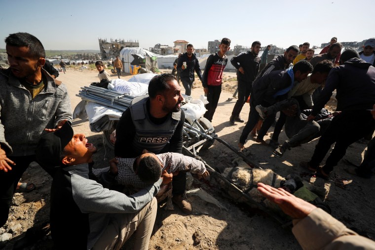 Palestinians hold the body of journalist Hossam Shabat, who was killed by an Israeli strike, according to medics, in the northern Gaza Strip, on March 24, 2025.