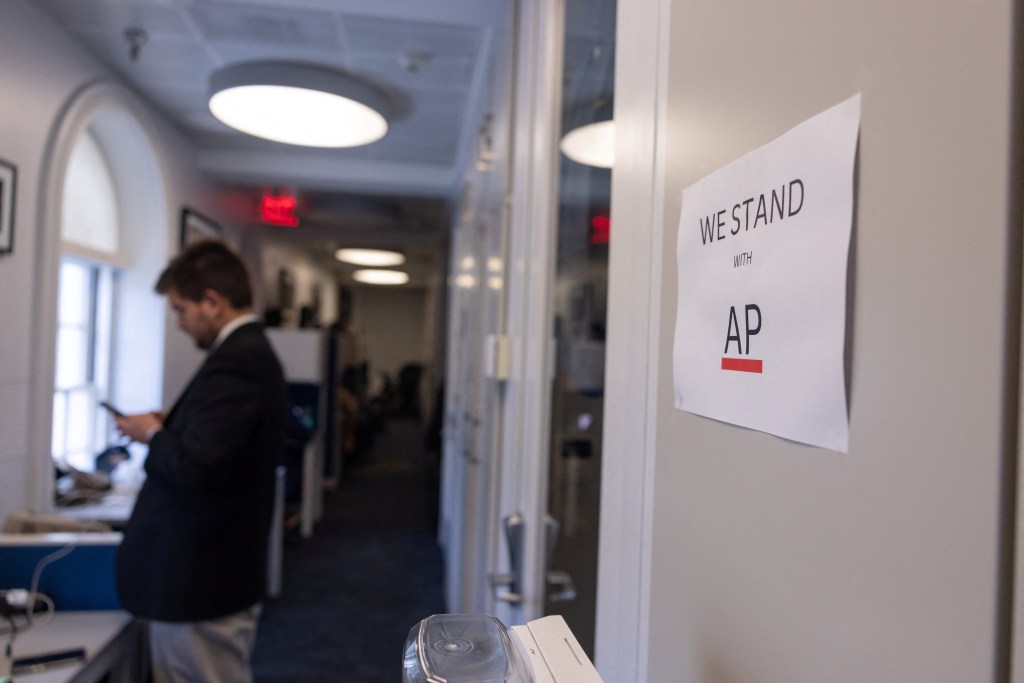 A journalist looks at his mobile phone next to a sign referencing the White House’s decision to bar the AP from pool events during a press briefing by White House Press Secretary Karoline Leavitt in Washington, D.C. on March 26, 2025